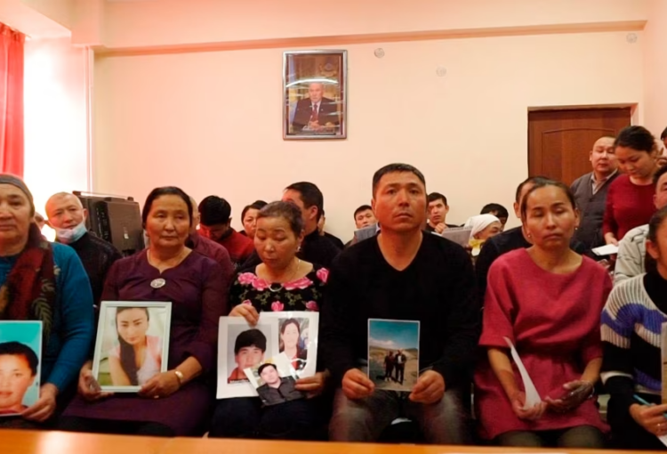 在哈萨克斯坦阿拉木图一个中国哈萨克族人组织的办公室里，人们手举在新疆失踪亲属的照片。（2018年12月7日）