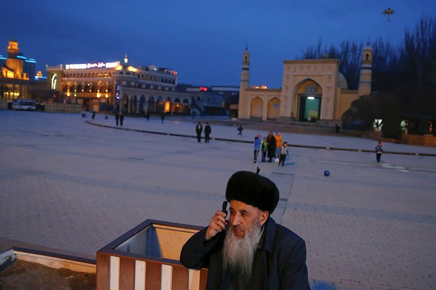 图为一名维吾尔人在新疆喀什是旧城区的艾提尕尔清真寺外使用手机通话